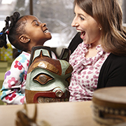 Image of a teacher smiling at a student holding a mask from the collection