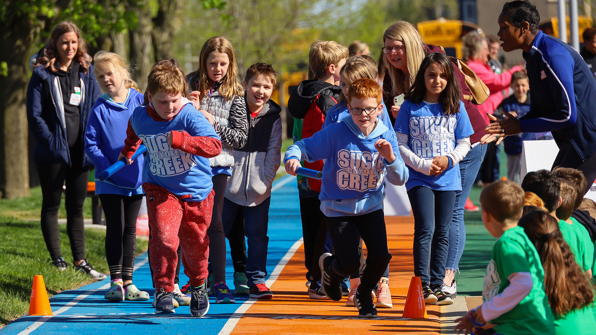 Children running in track lanes.