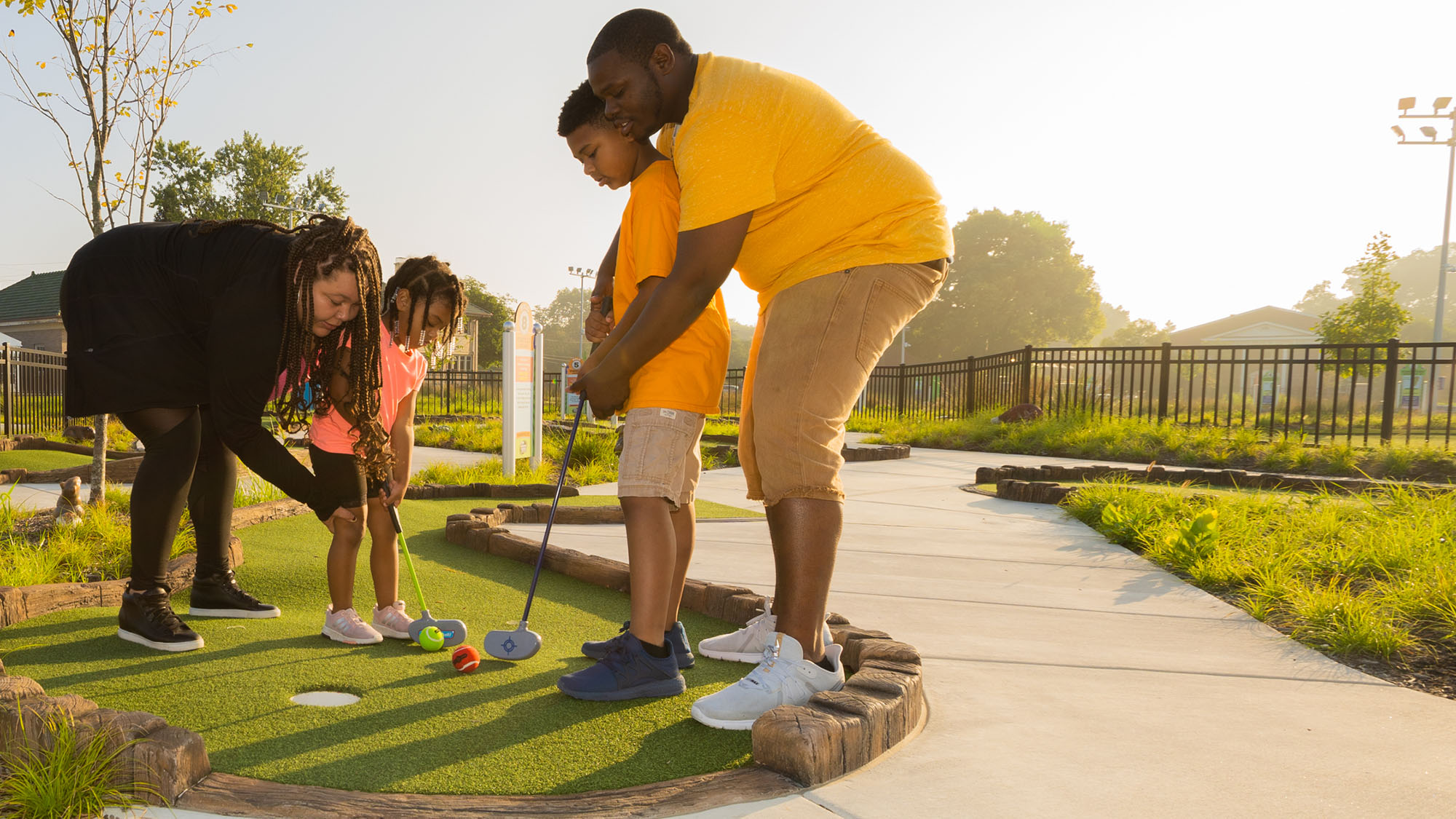 Grown-ups helping children putt.