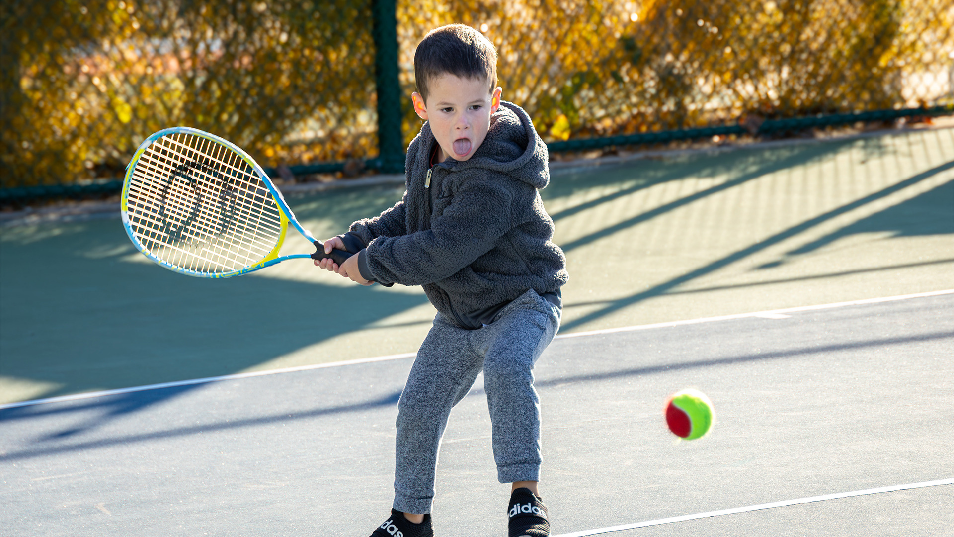 Child hitting a ball with a tennis racquet.