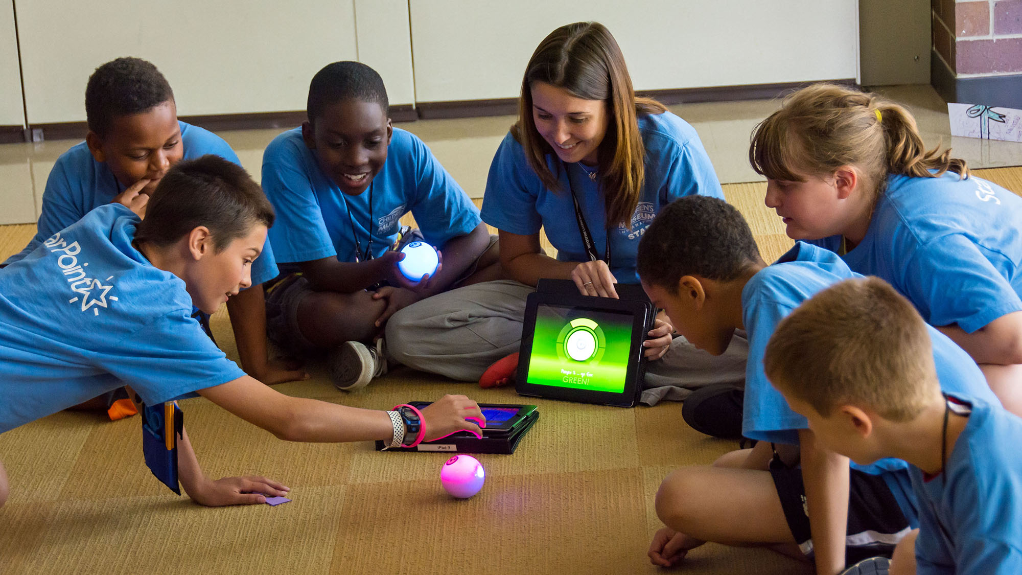 Children and staff member playing game on the floor.