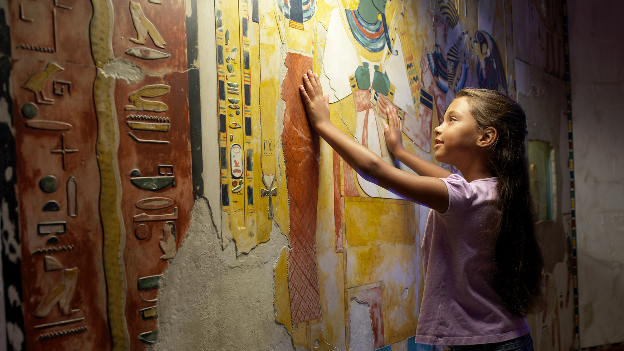 Child touching wall of hieroglyphics. 