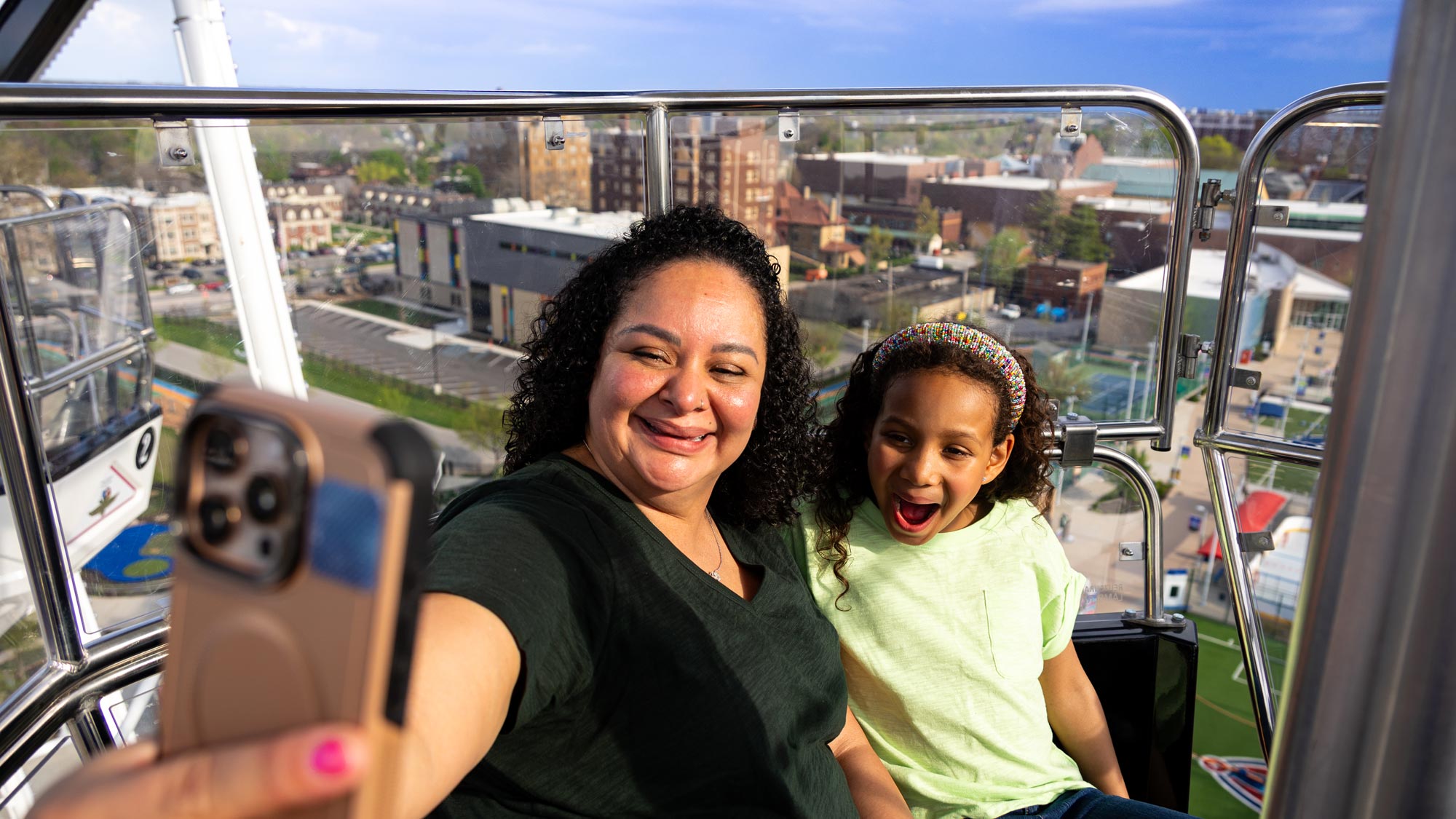 Grown-up and child taking a selfie while riding the Centennial Ferris Wheel.