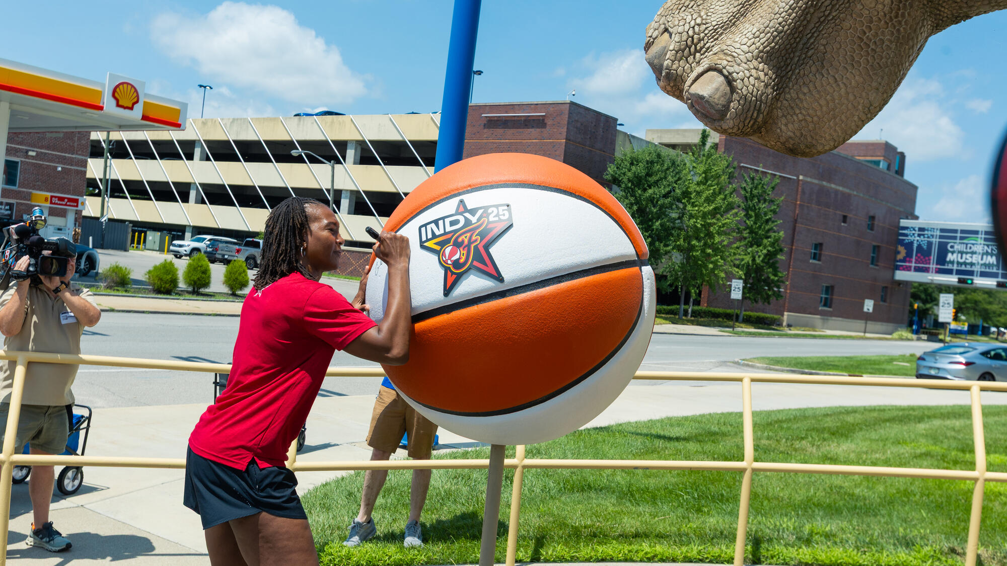 Tamika Catchings signing a giant WNBA basketball with the 2025 All-Star Game host committee logo on it.