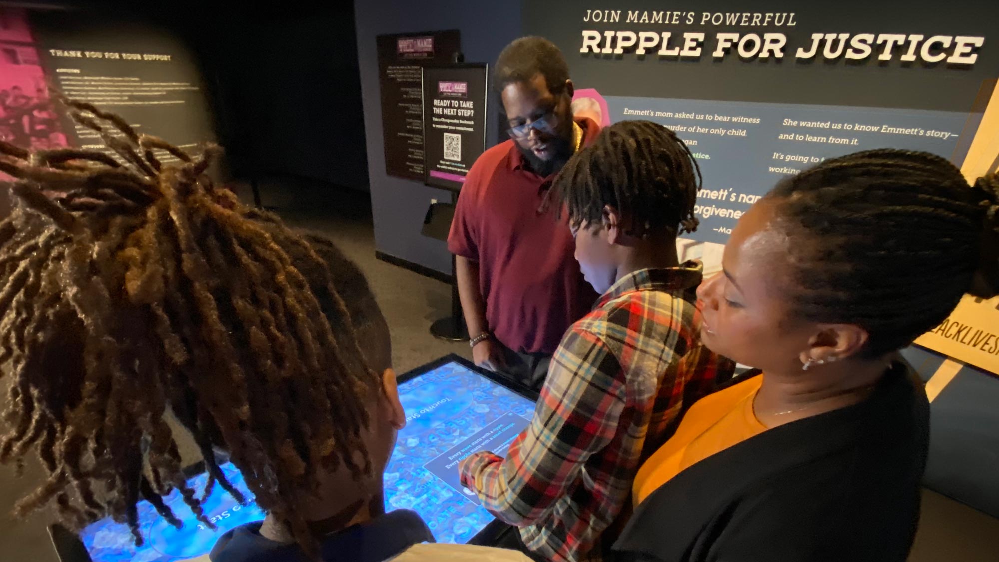 Family gathered around a display in the Emmett Till and Mamie Till-Mobley: Let the World See exhibit.