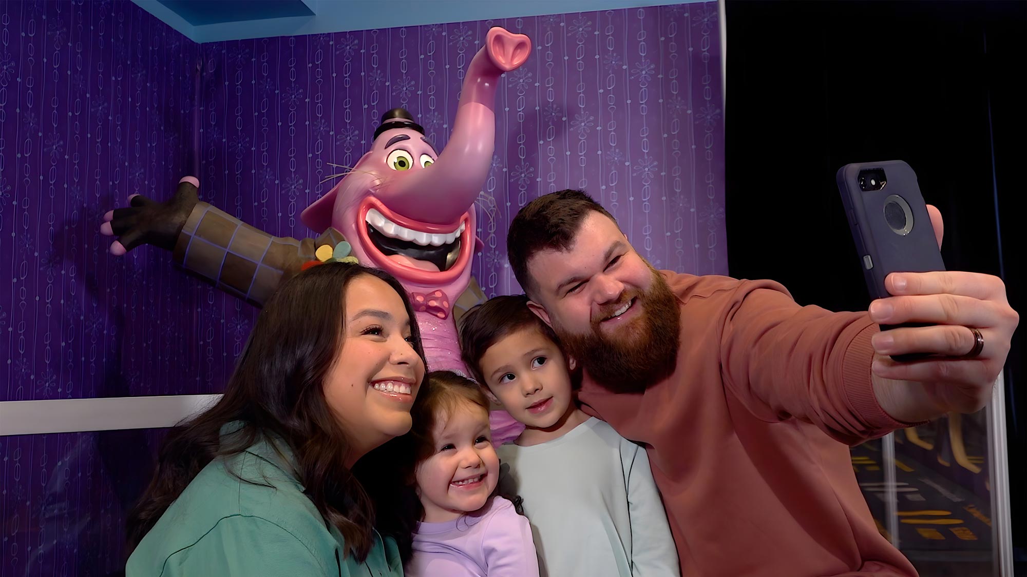 Family posing for a selfie in the Emotions at Play with Pixar's Inside Out exhibit.