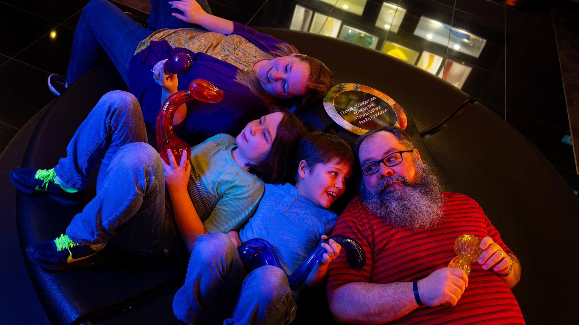 Family sitting in a revolving couch looking up at the Fireworks of Glass display.