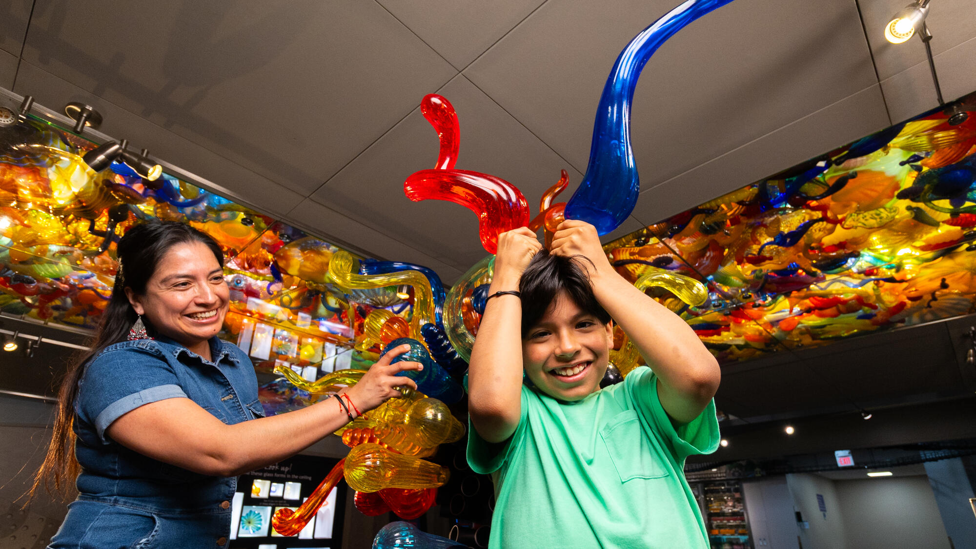 Child holding two plastic tubes over head like they're horns.