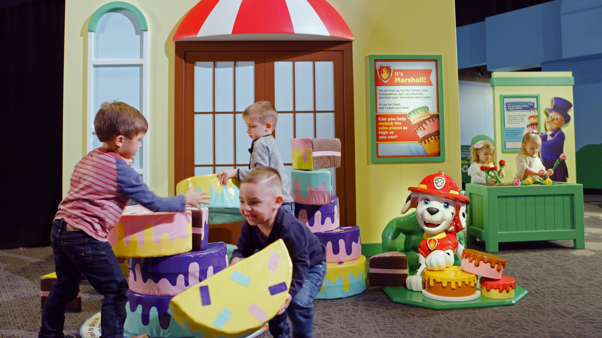 Children building a cake tower in the PAW Patrol exhibit.