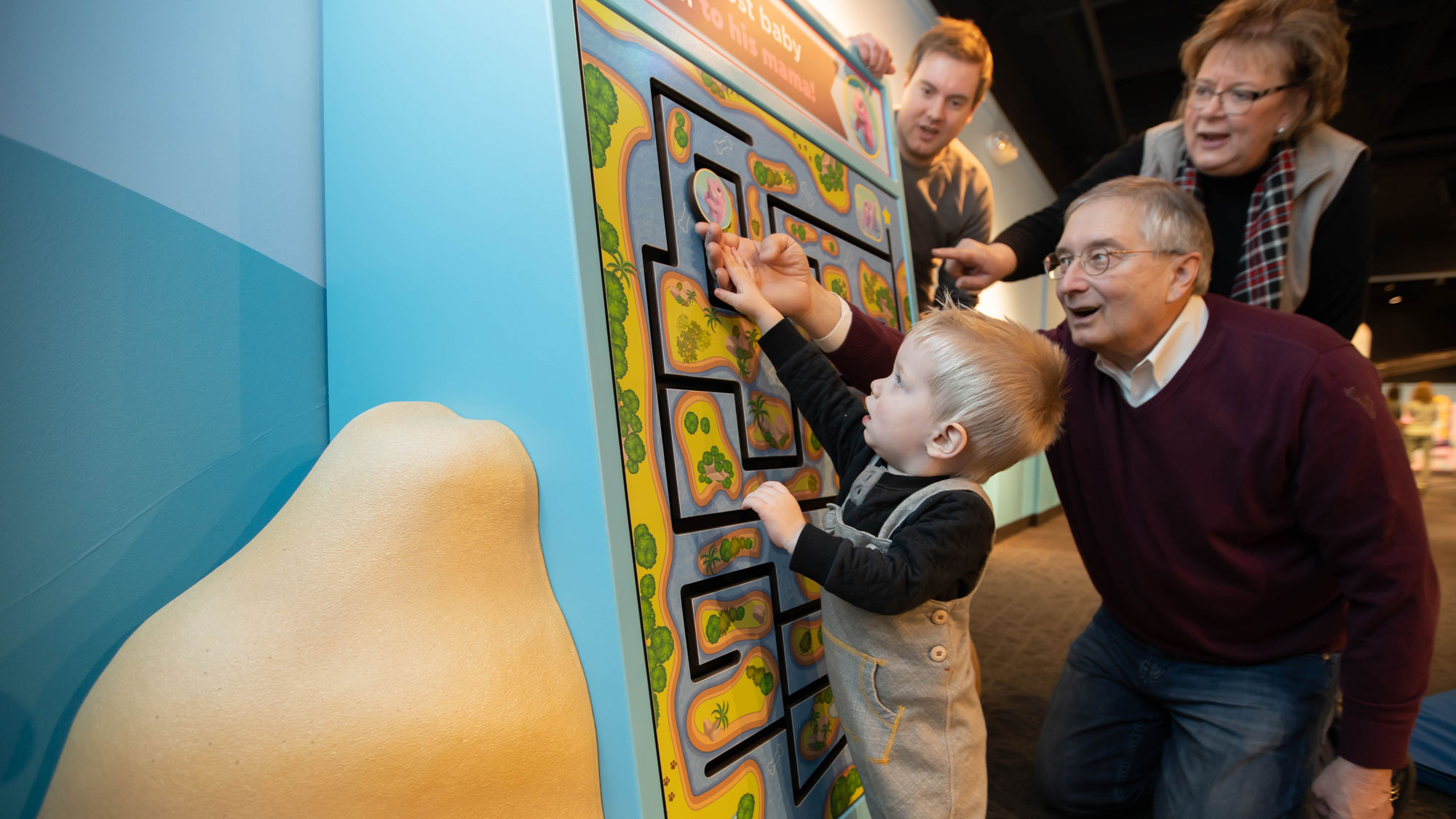 Grown-up and child navigating a maze attached to a wall.