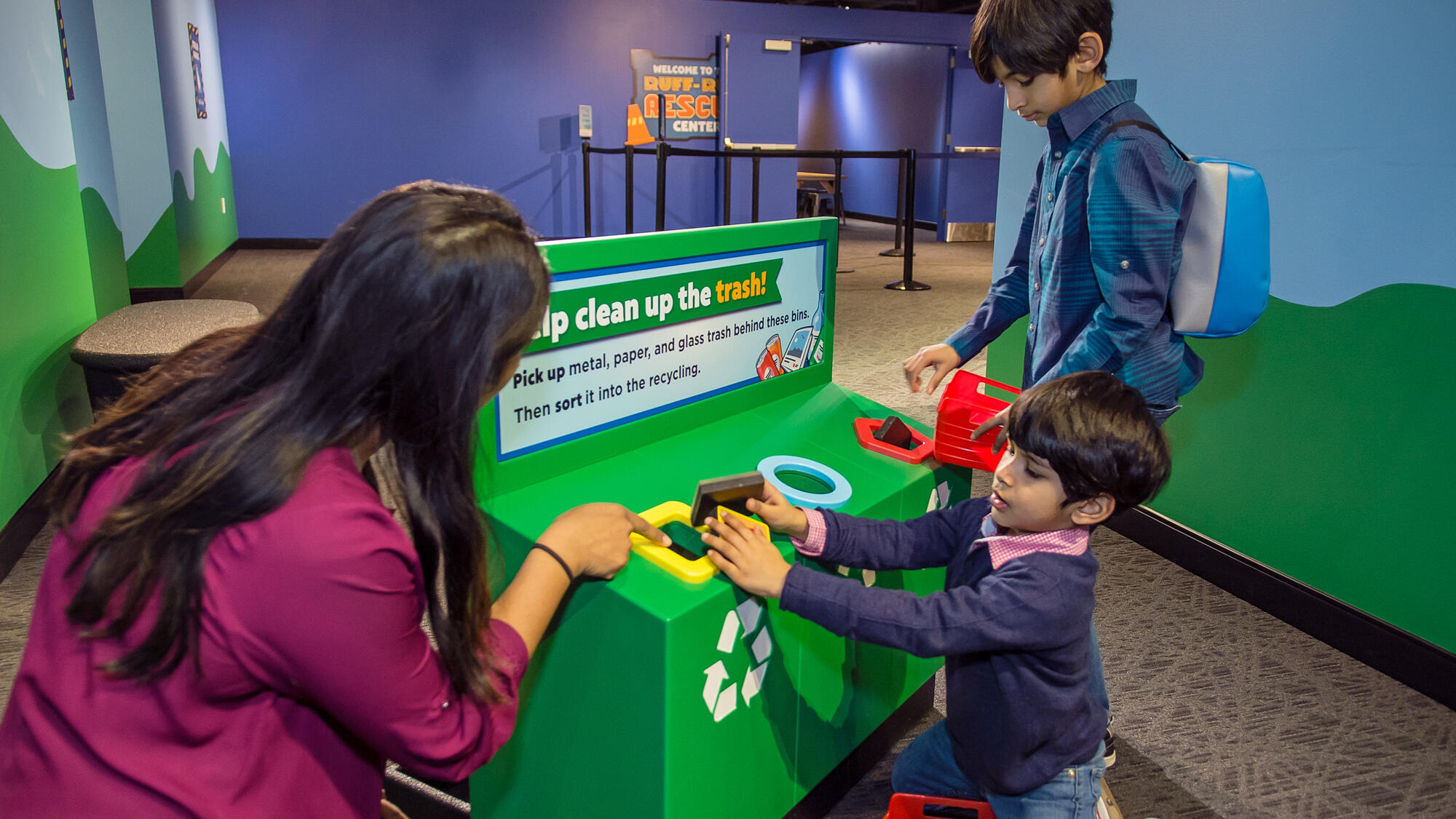 Child sorting objects in a pretend-play recycling bin.