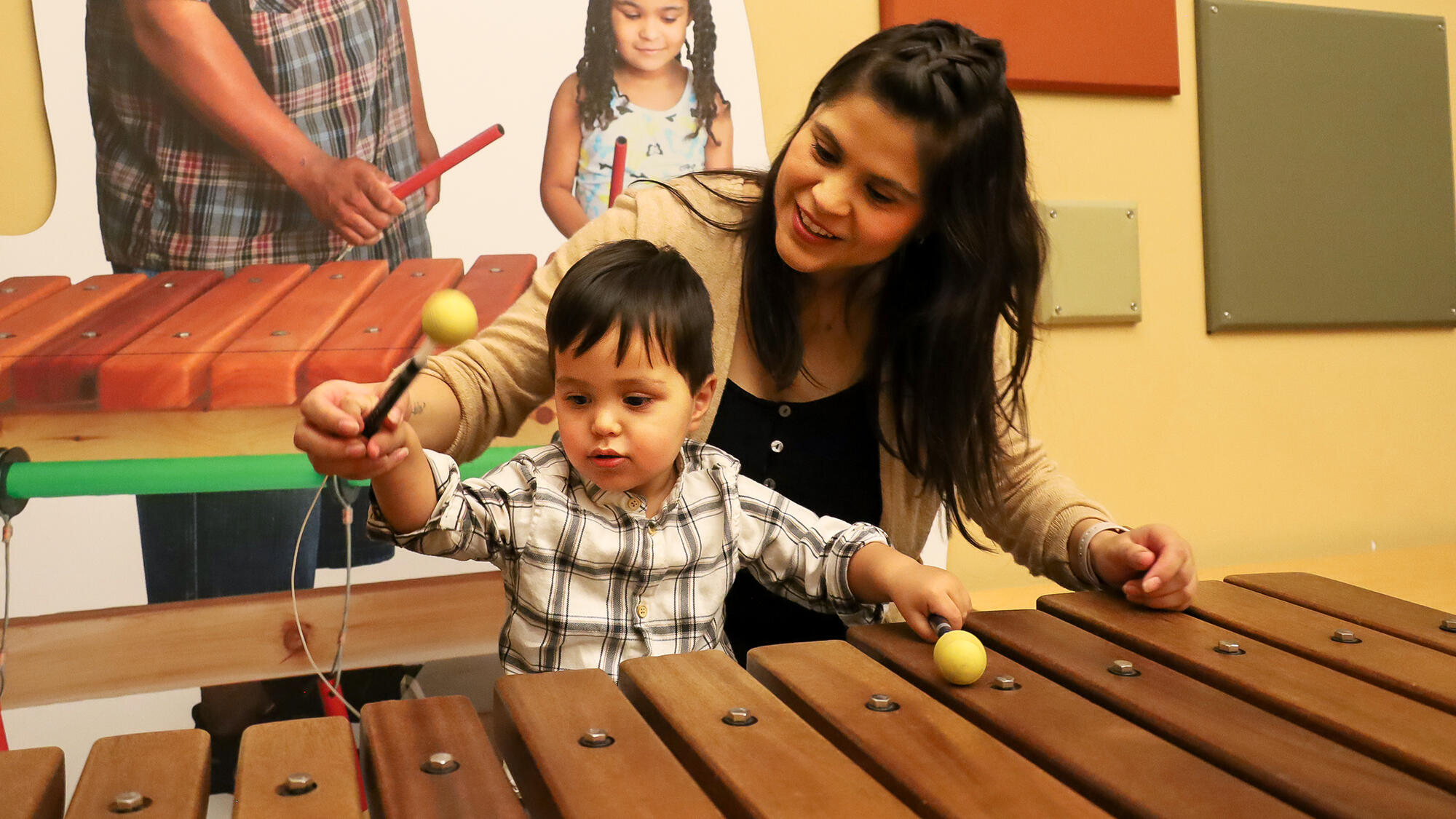 Child and grown-up playing on a xylophone.
