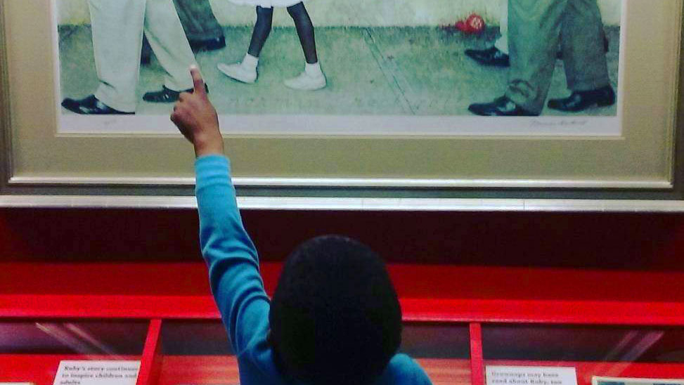 Child pointing at the Norman Rockwell painting, The Problem We All Live With.