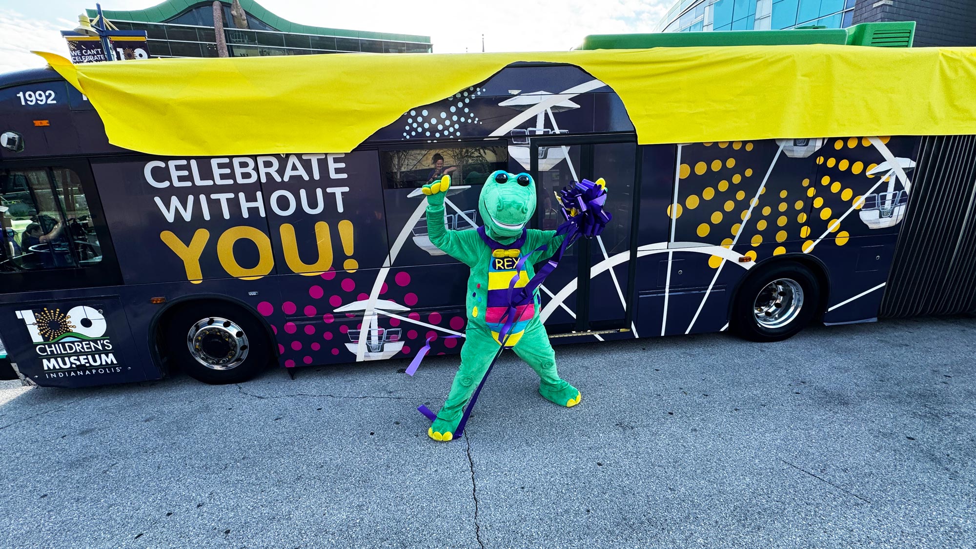 Mascot Rex unwrapping the IndyGo Birthday Bus.