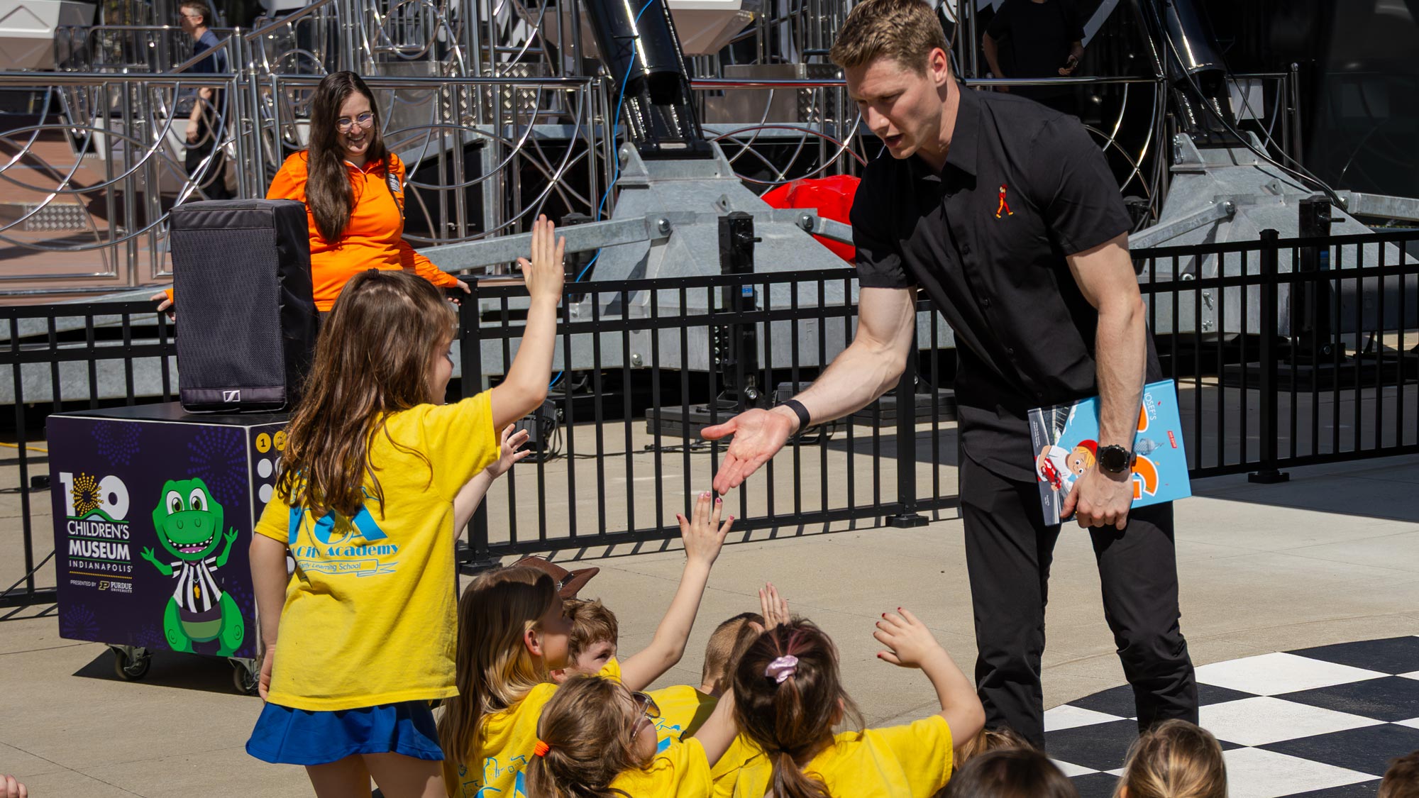 Josf Newgarden receiving high fives from students.