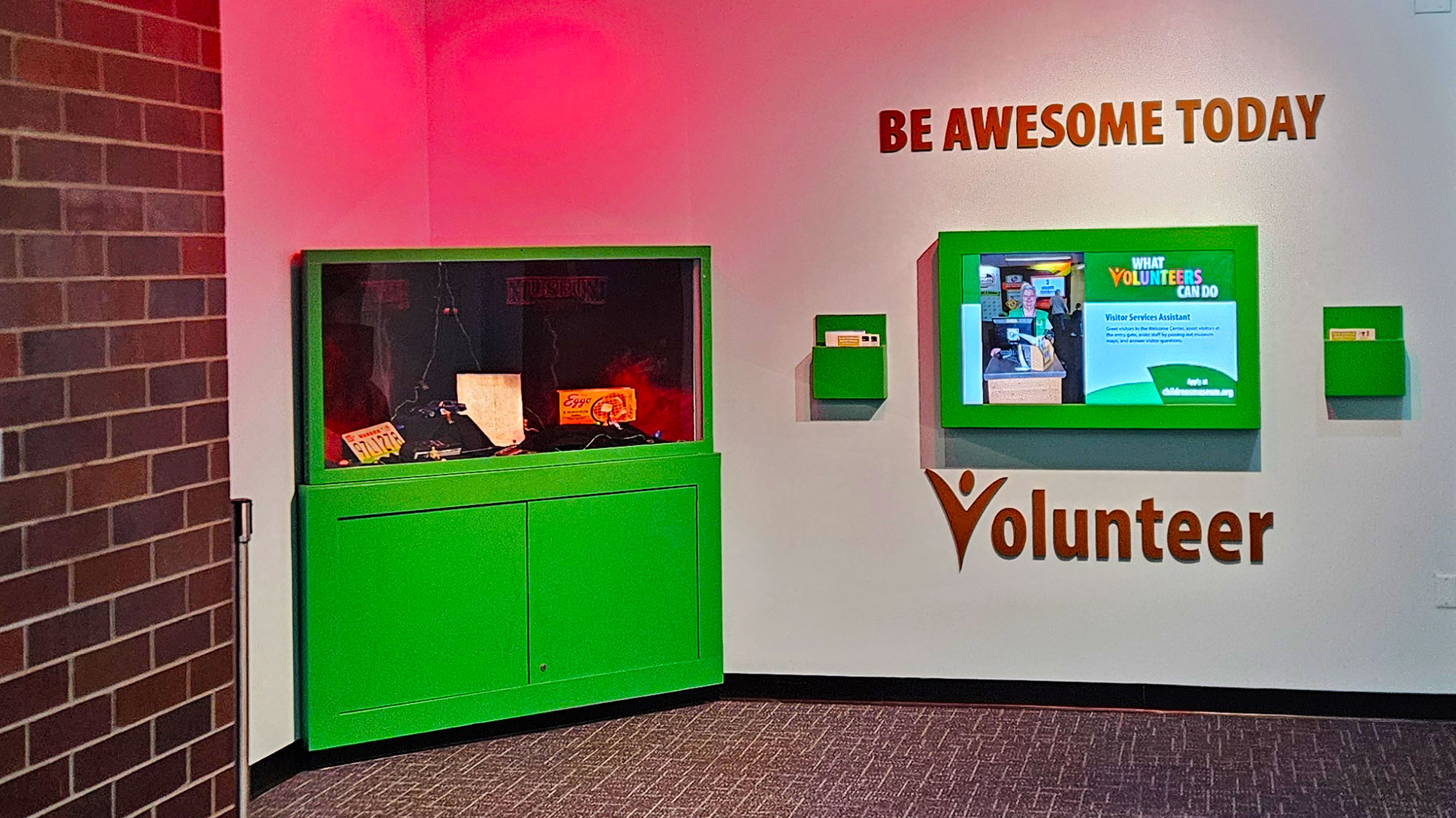 The Stranger Things inspired Museum Things case next to a sign that says "Be awesome today. Volunteer."