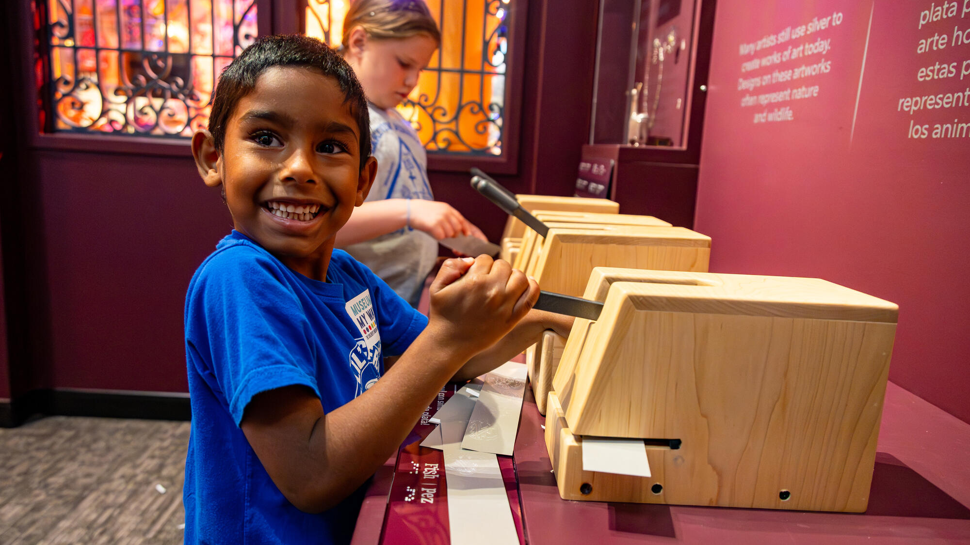 Child pushing a lever to add a design to a bracelet.
