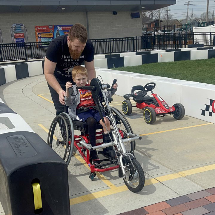 Grown-up attaching hand-cycle attachments to wheelchair.