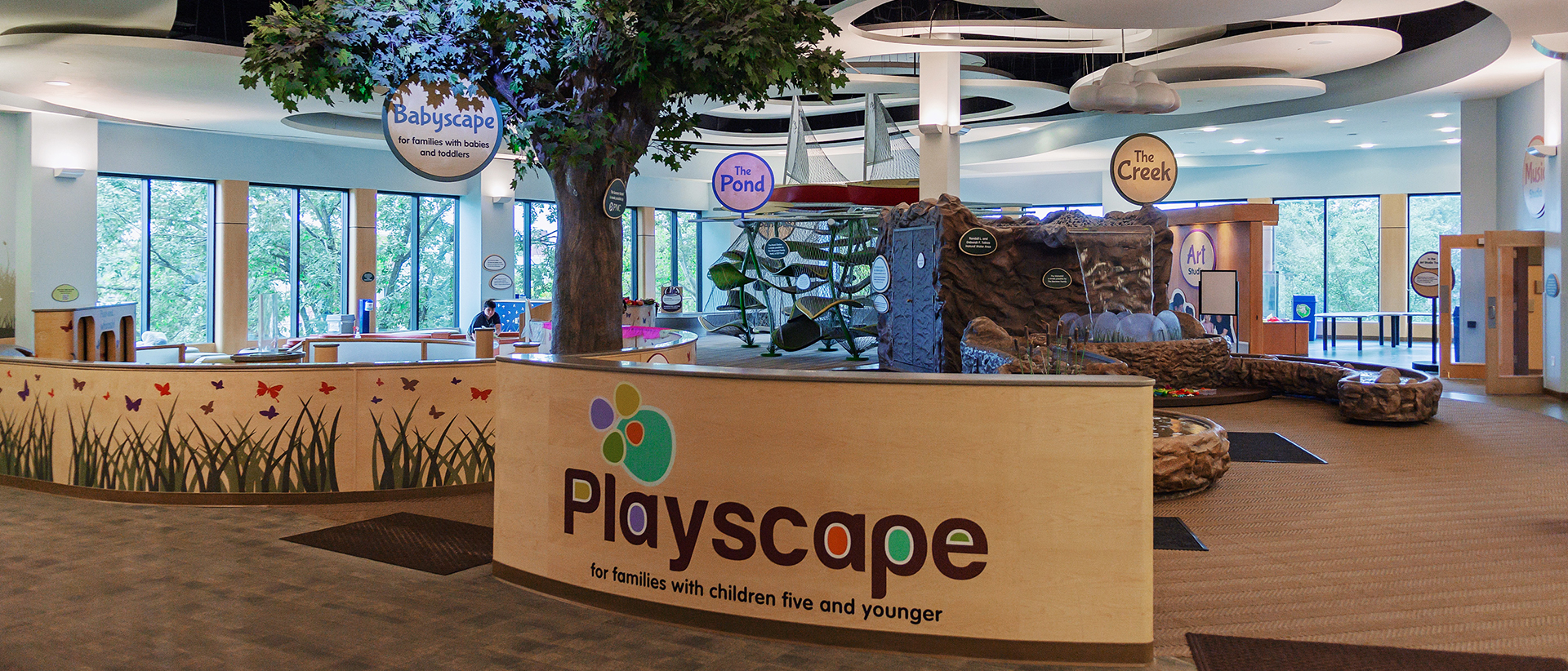 Photo of the exhibit, including a giant tree, a climbing area, and water table.