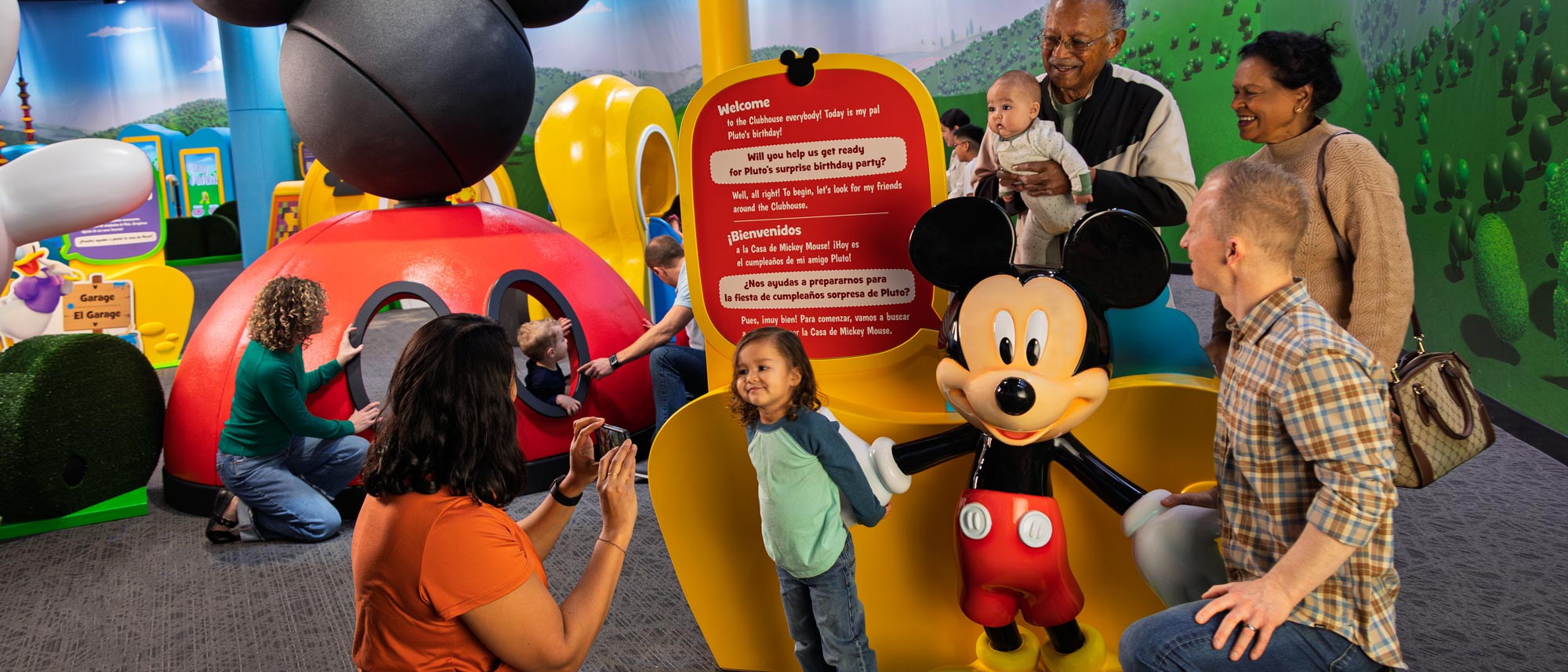 Families posing with a statue of Mickey Mouse in the exhibit.