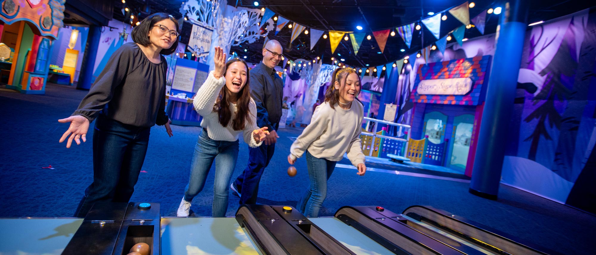 Family playing Skee-Ball inside the WinterFaire exhibit.