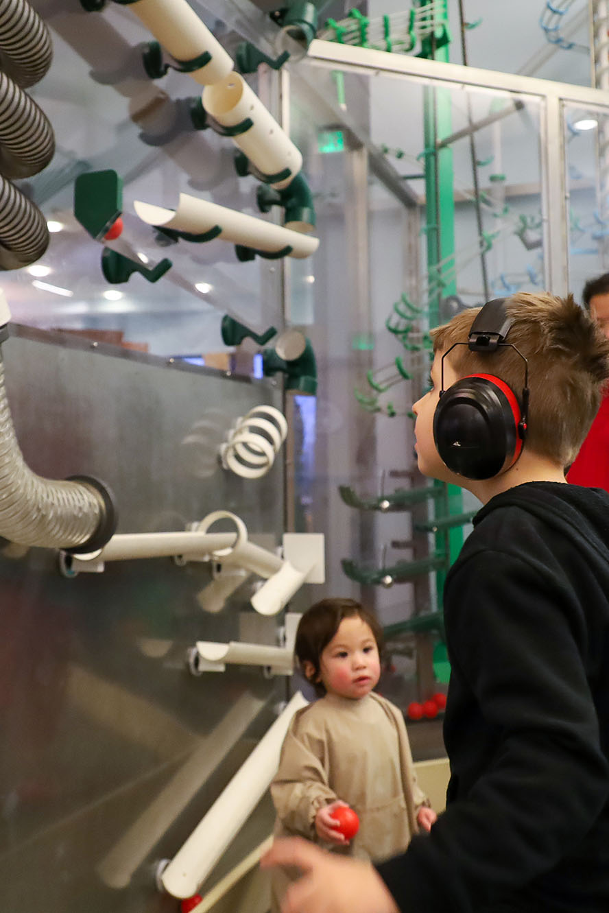 Person wearing noise-canceling headphones and playing in an exhibit.