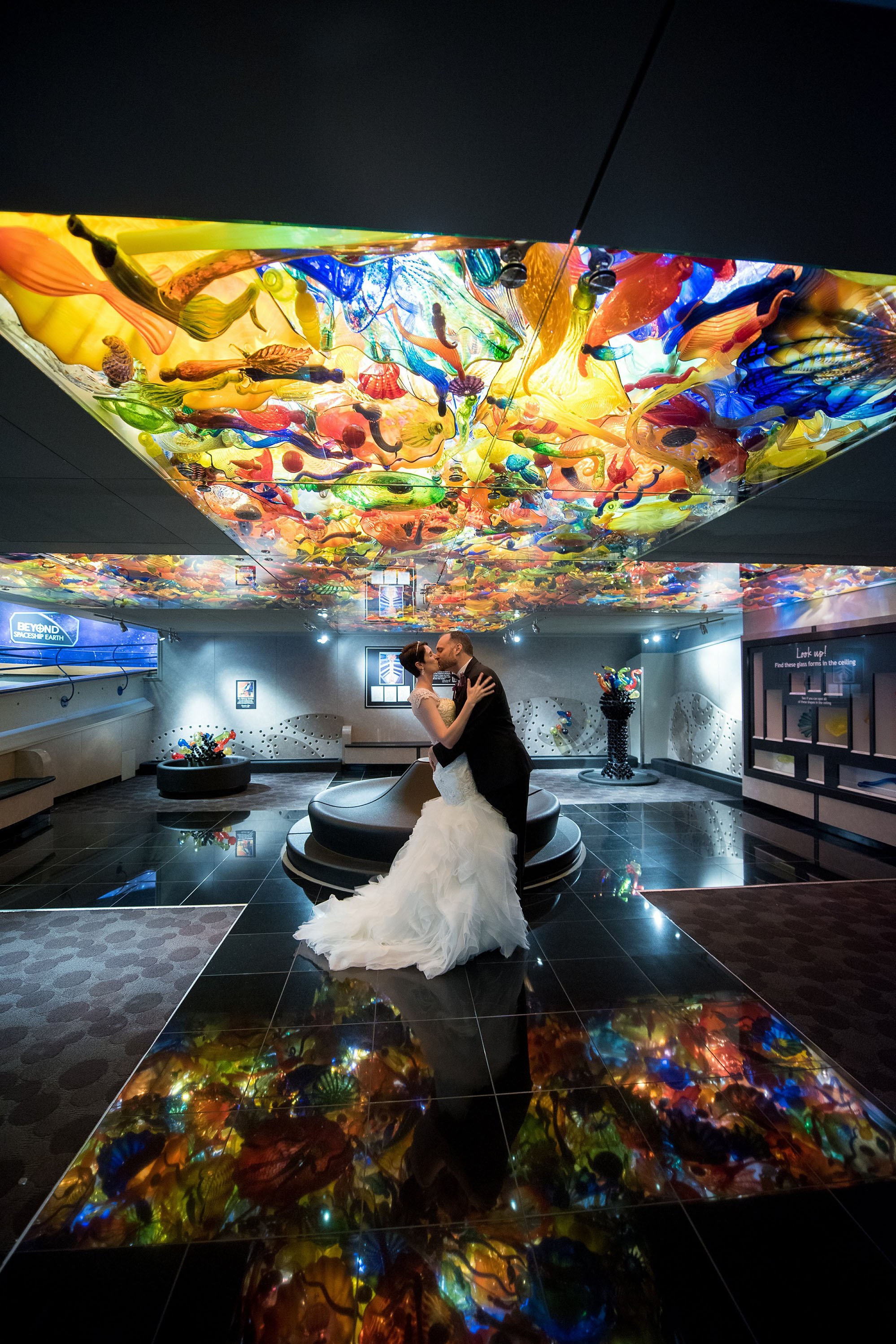 Bride and Groom under colorful glass ceiling.