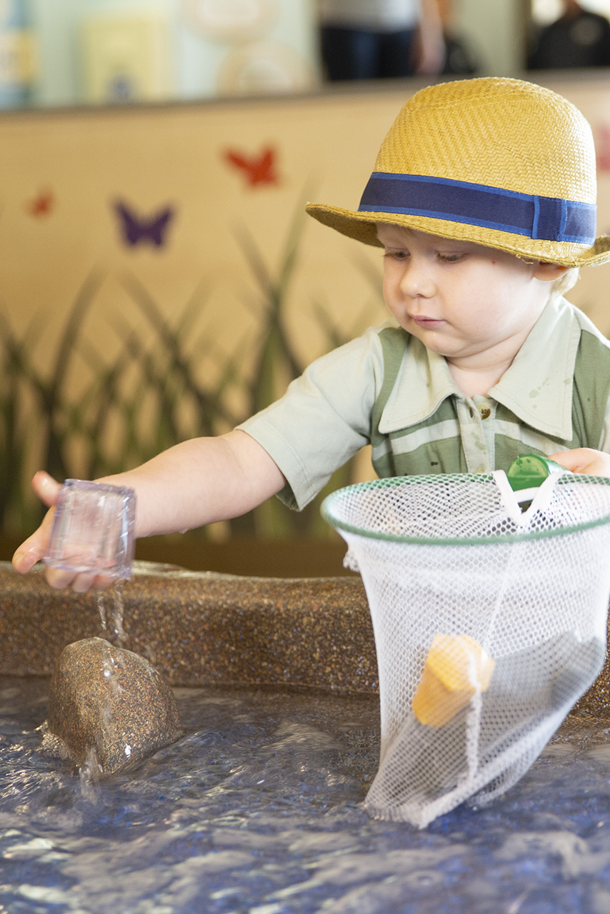 Child holding a net and playing with water.