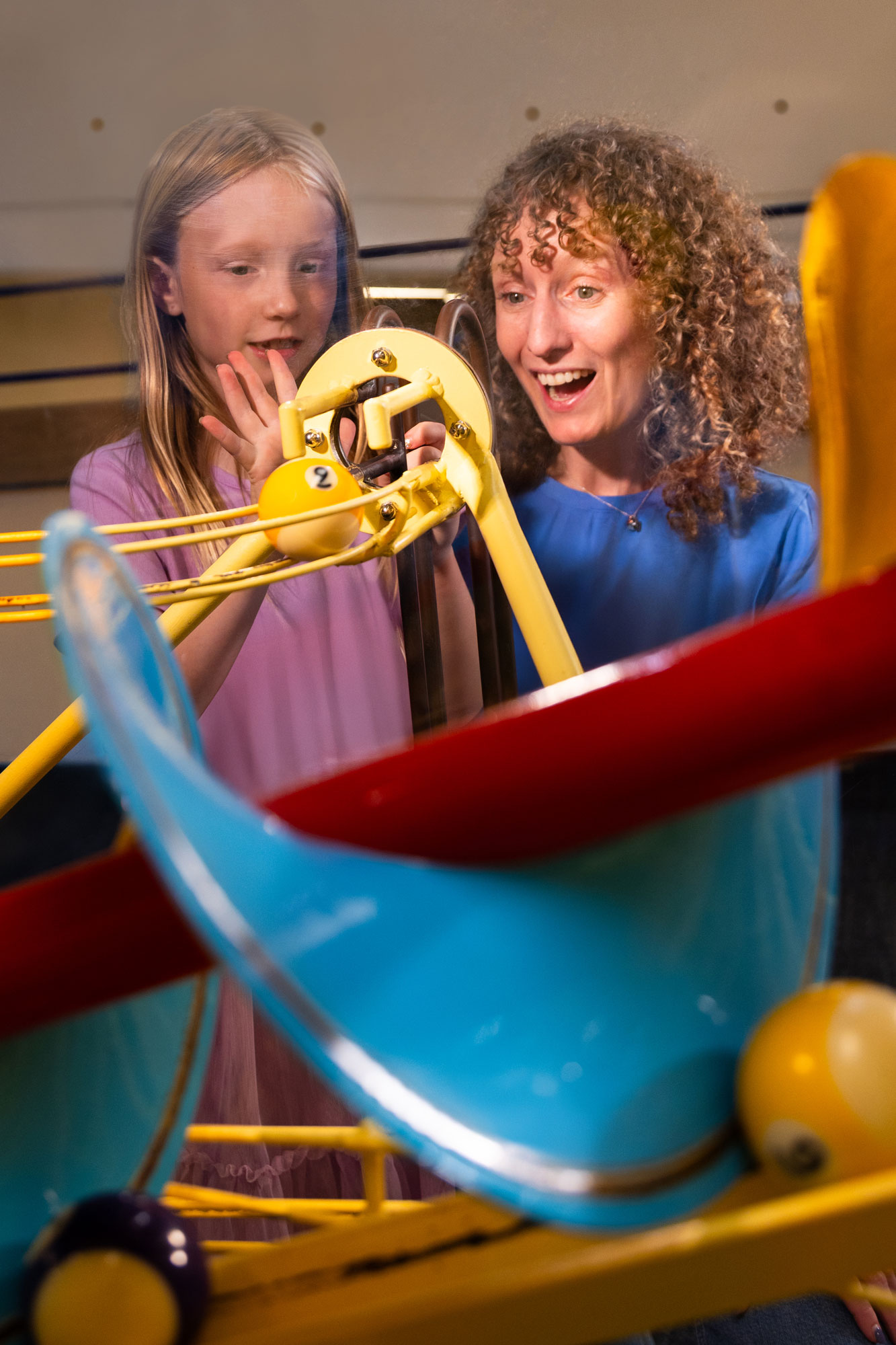 Child and grown-up looking at a Rube Goldberg contraption.