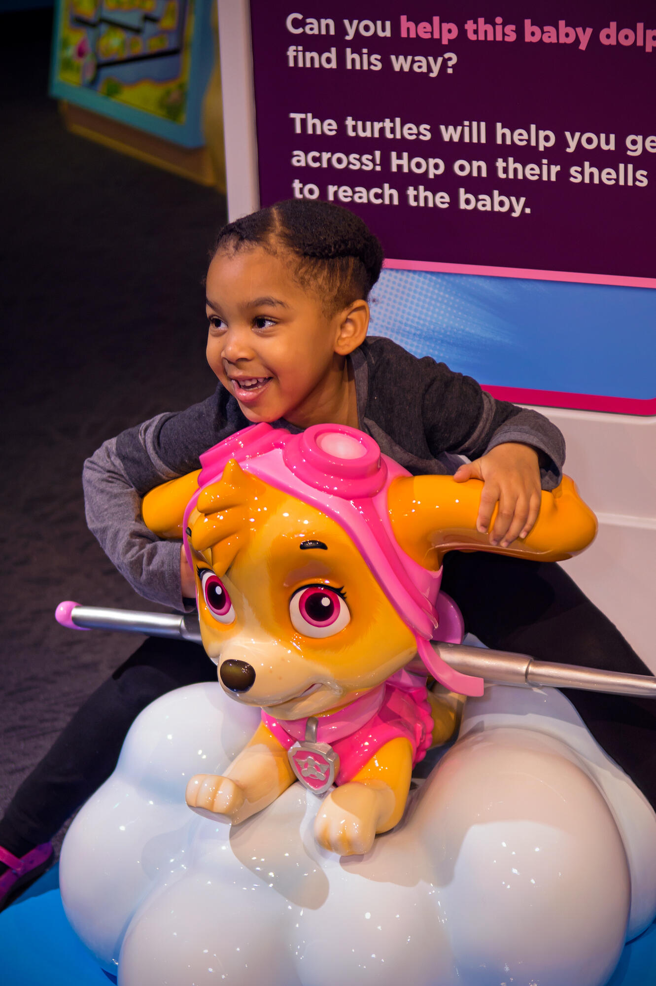 Child posing with sculpture of Skye from PAW Patrol. 