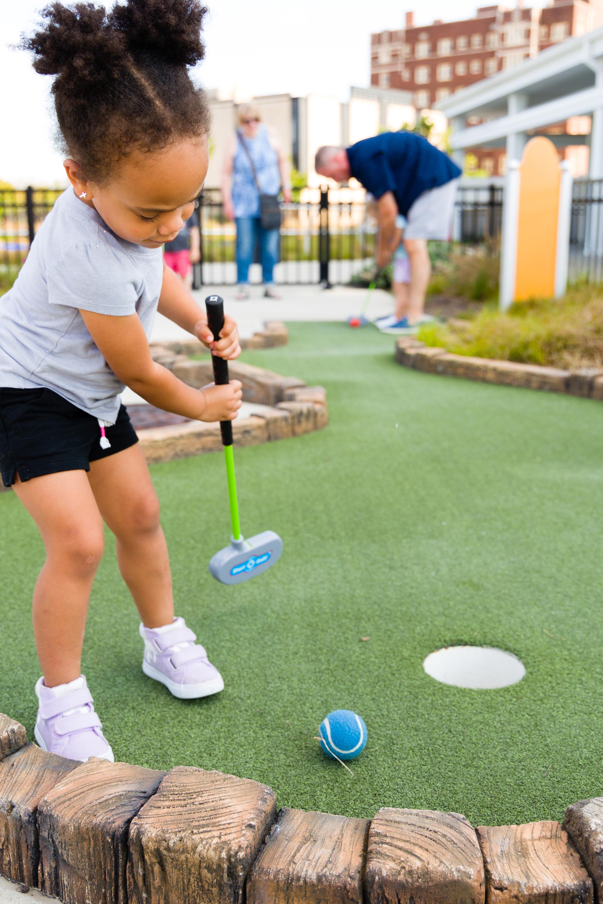 Toddler putting golf ball.