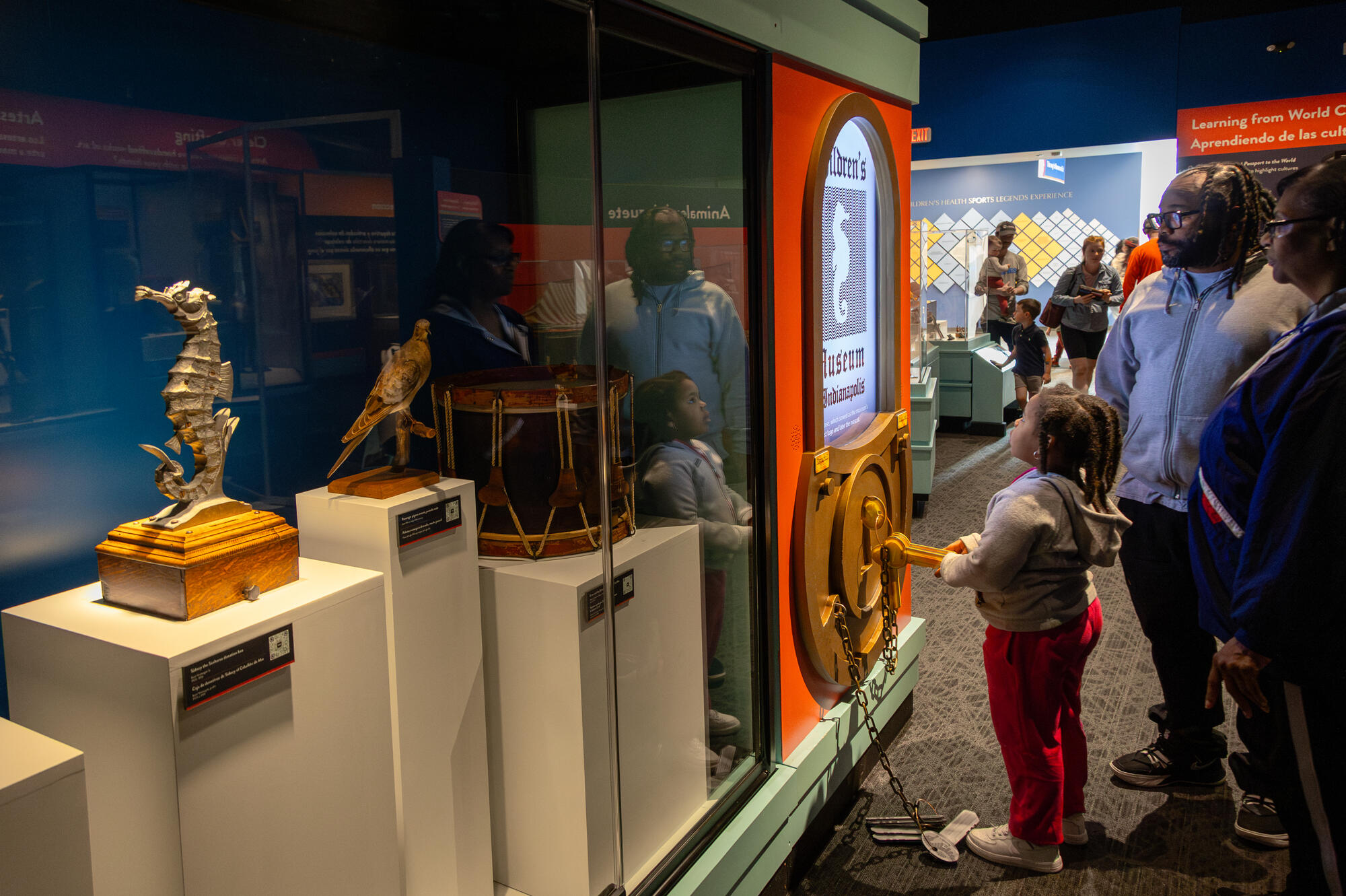 Family looking at the Stories from 100 Years exhibit, including a mounted passenger pigeon and seahorse sculpture.