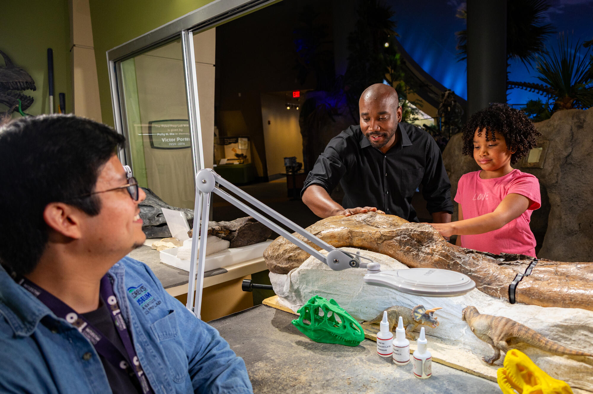 Grown-up and child touching a dinosaur fossil in the paleo prep lab.
