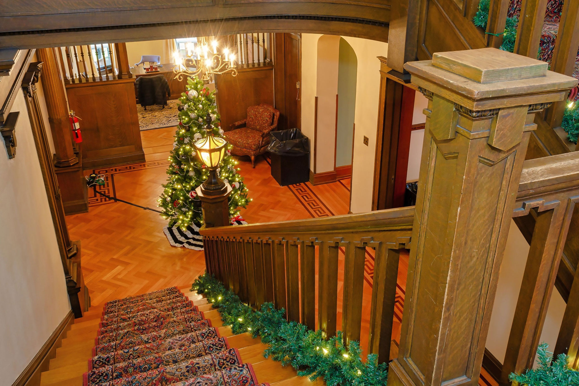 Evergreen tree with holiday lights at the bottom of a stairway with evergreen bunting.