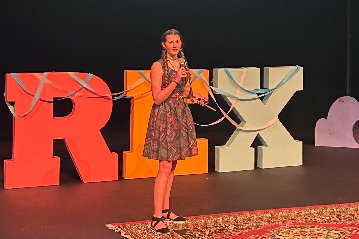 Rory standing in the middle of the stage in front of a giant REX sign