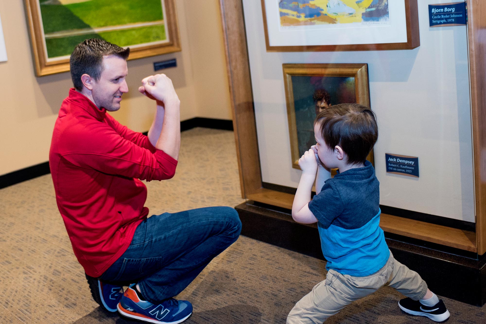 Child and grown-up posing like the boxer painting they've been looking at.