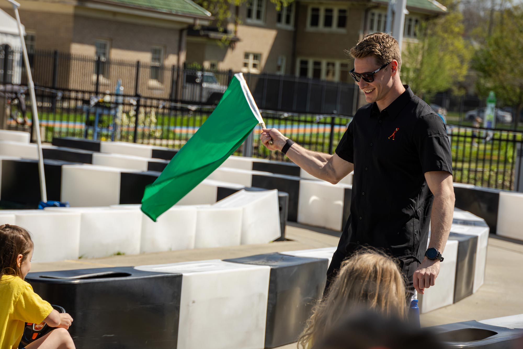 Josef Newgarden waving a green flag in the race track experience at the Riley Children's Health Sports Legends Experience.