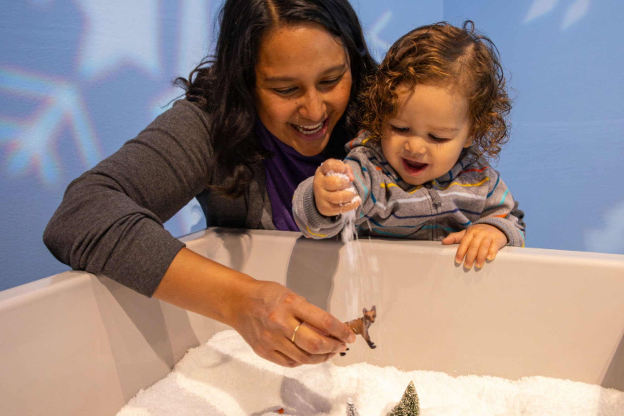 Grown-up and child playing in a box of pretend-play snow.