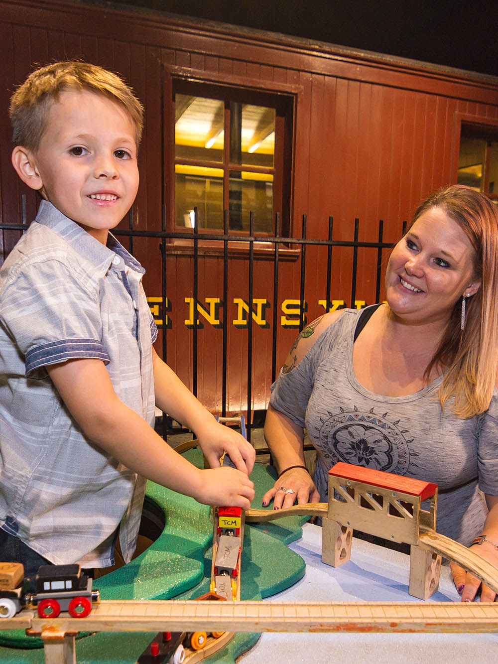 Grown-up and child playing with toy trains.