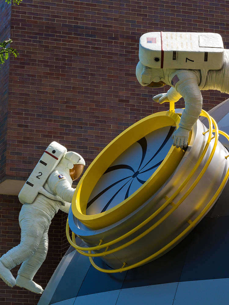 Sculptures of astronauts space walking outside museum.