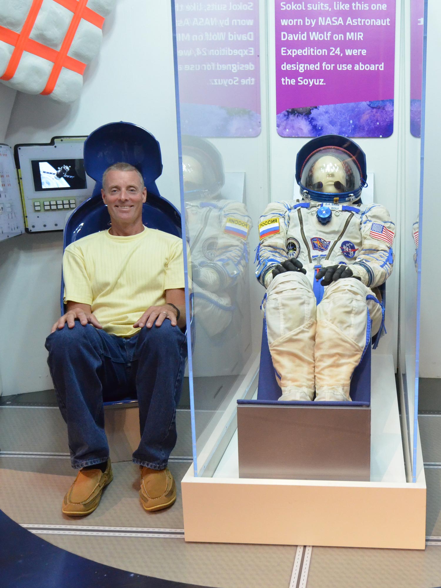 Grown-up sitting in a chair in a Soyuz spacecraft interactive inside Beyond Spaceship Earth exhibit.