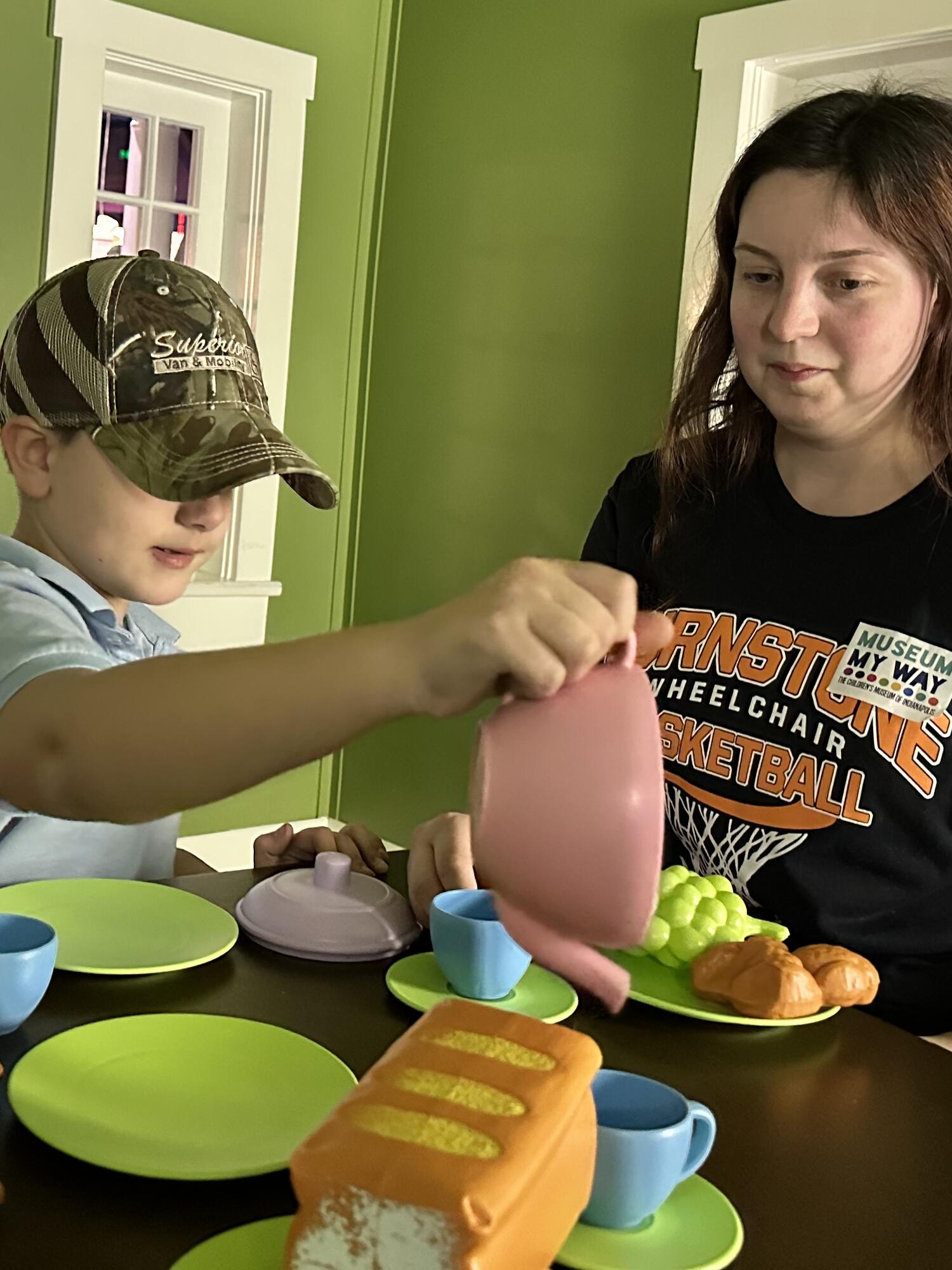 Child and grown-up having a tea party in a playhouse.