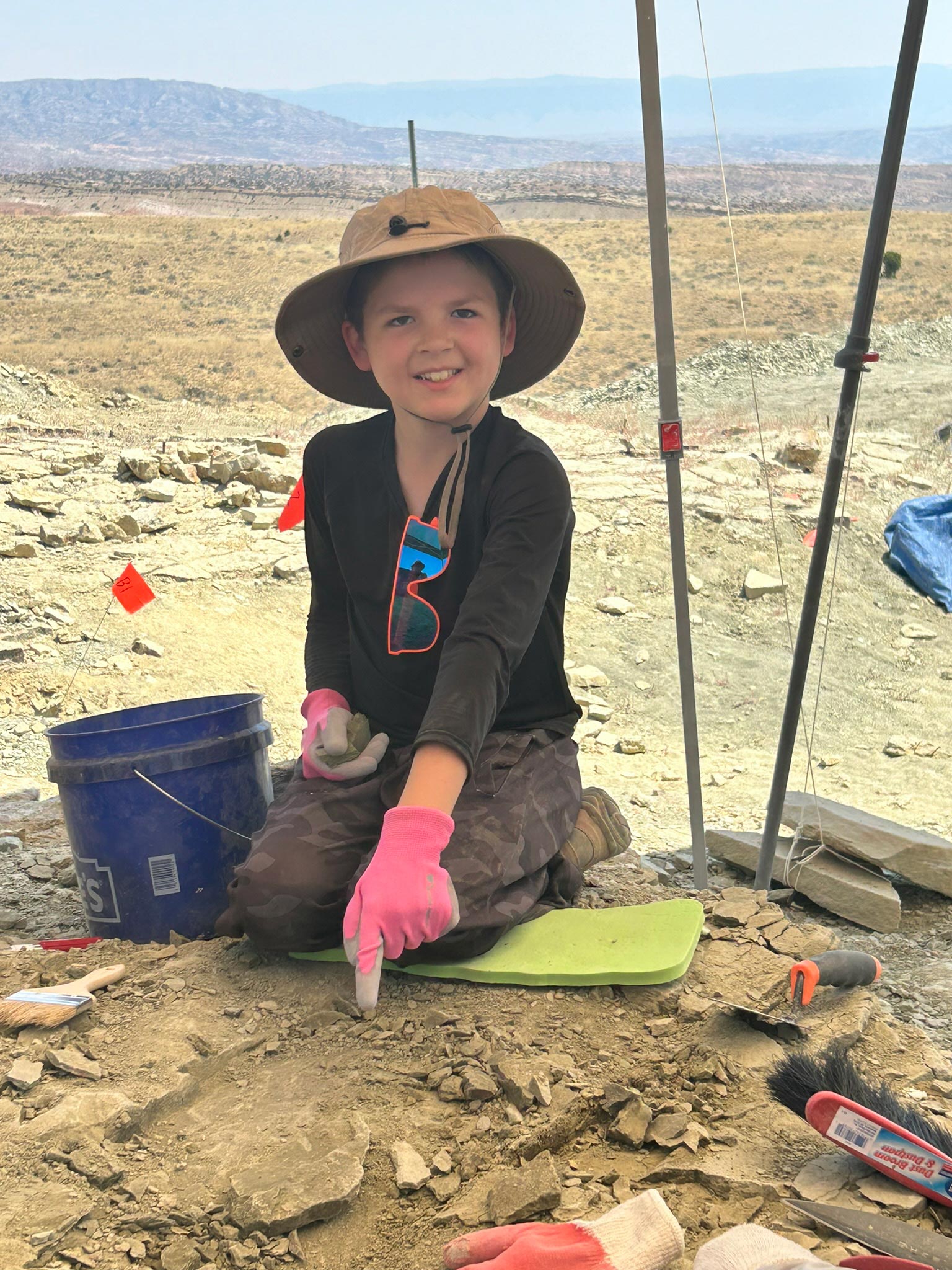 Child pointing at fossil in the ground. 