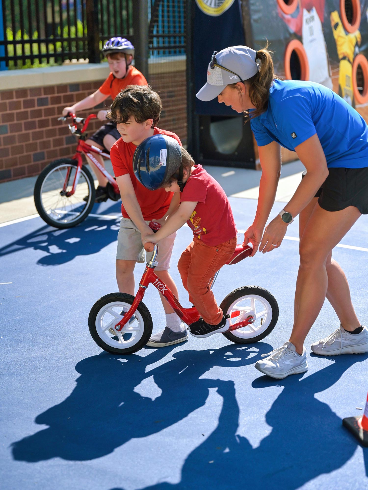 Grown-up and child helping child ride bike.