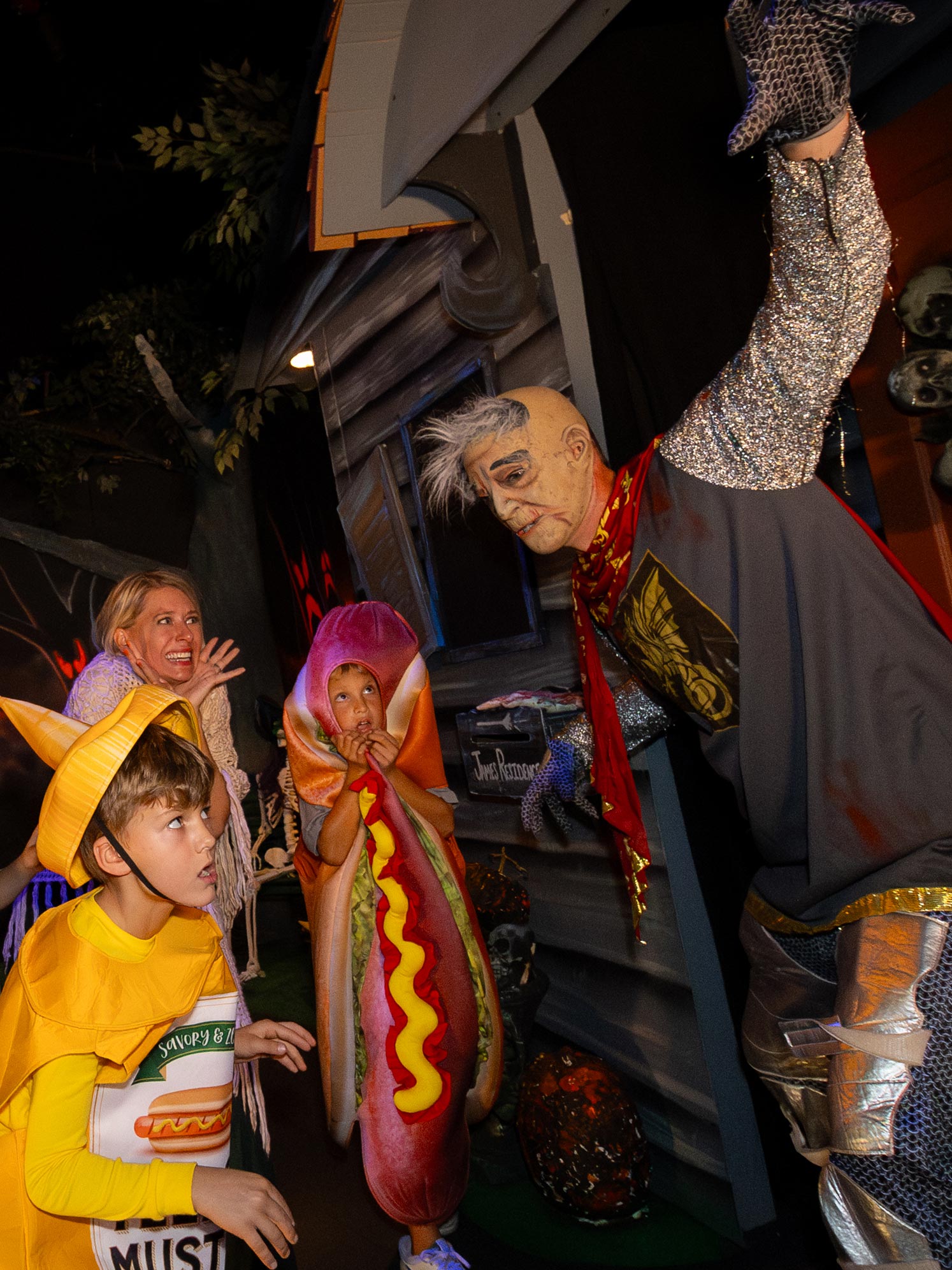 Character in mask jumping out at family walking through Haunted House.