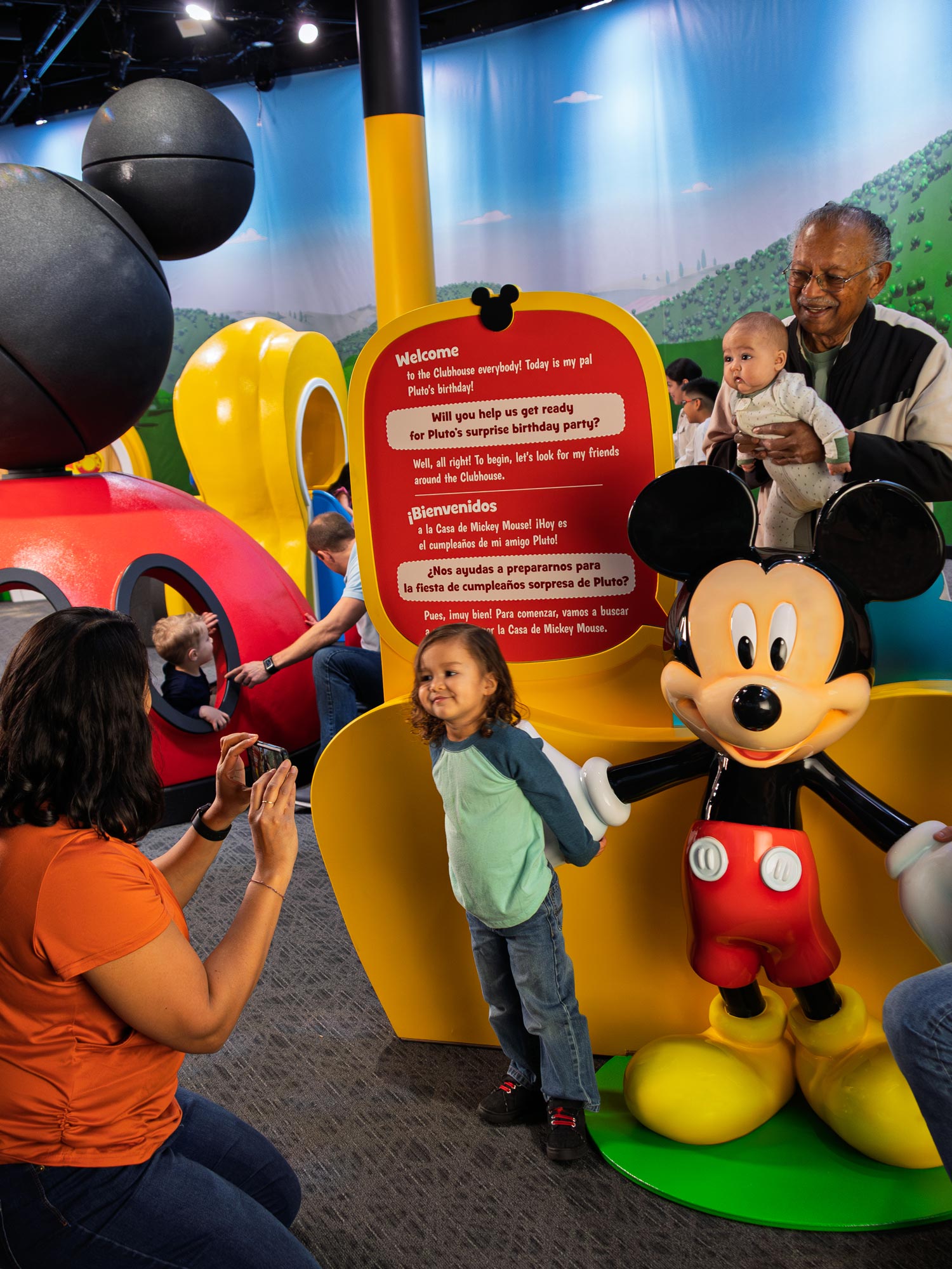 Families posing with sculpture of Mickey Mouse.