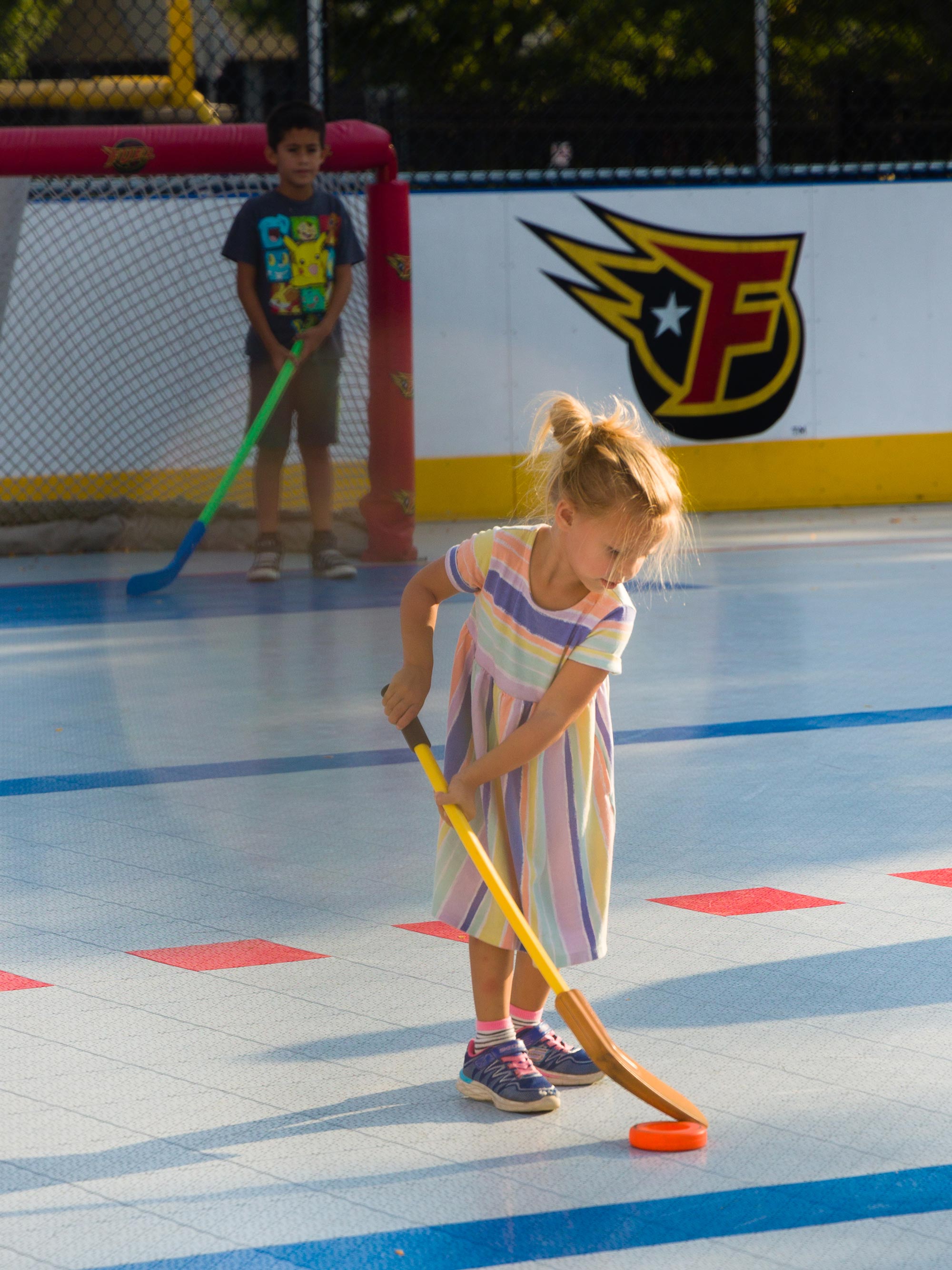 Child using hockey stick to move hockey puck.