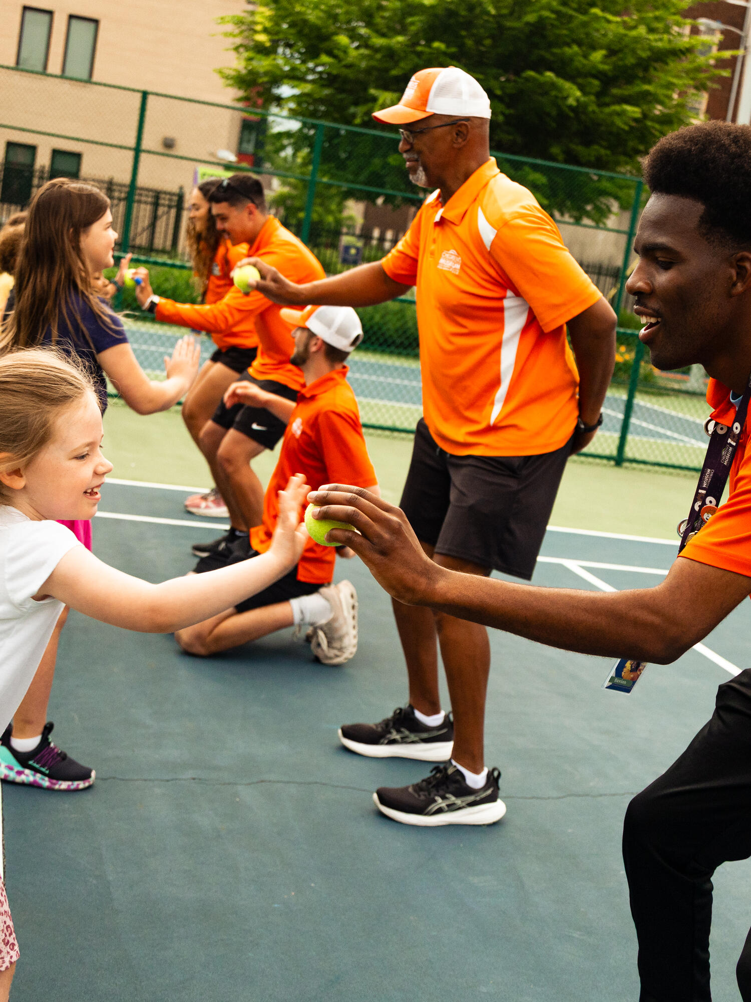 Coach leading child through tennis drills.