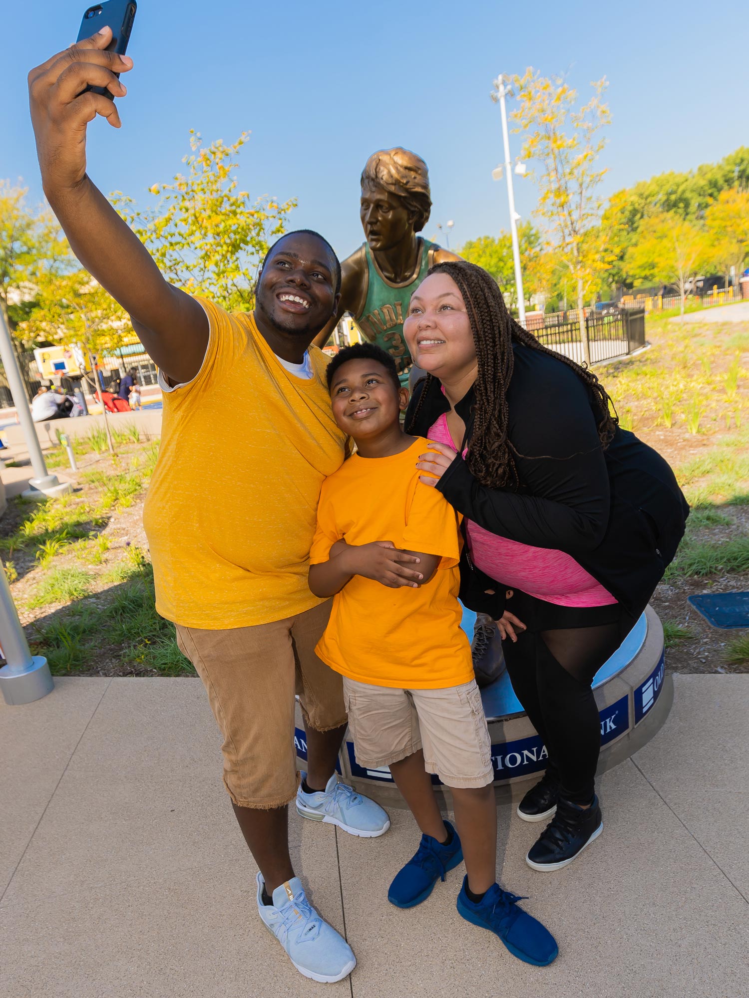 Family taking a selfie in front of the Larry Bird statue.