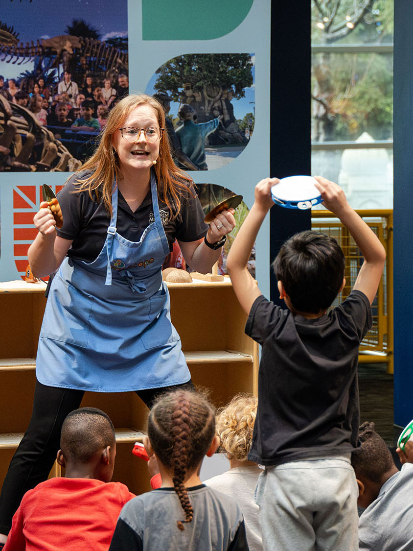 Grown-up telling a story while a child holds up a tambourine. 